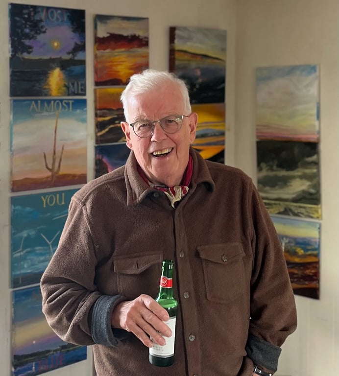 Ralph Reed in his studio with his paintings behind him
